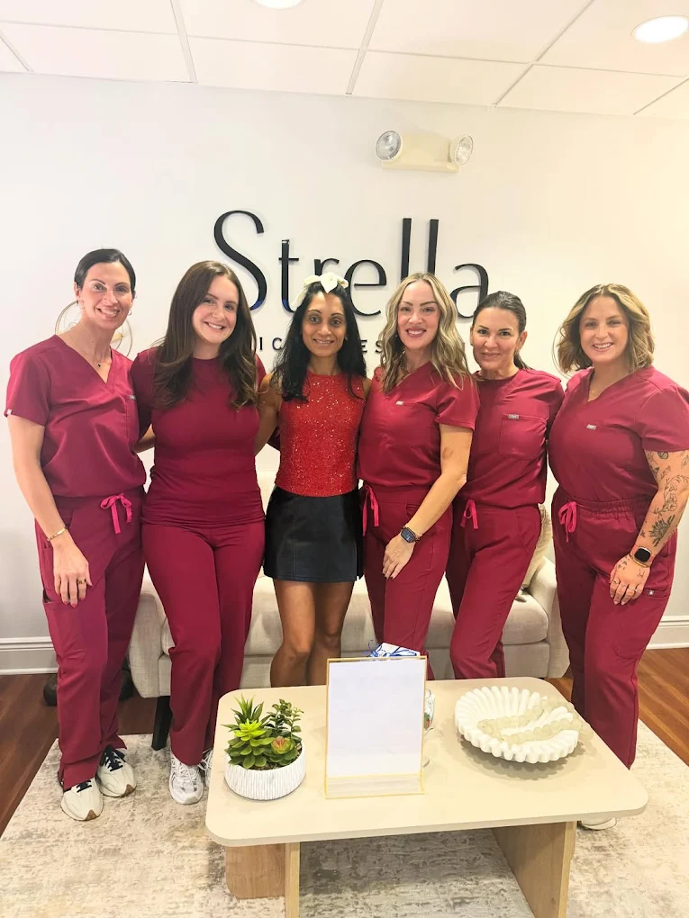 Team photo of Strella Medical Aesthetics staff standing together in clinic wearing matching uniforms